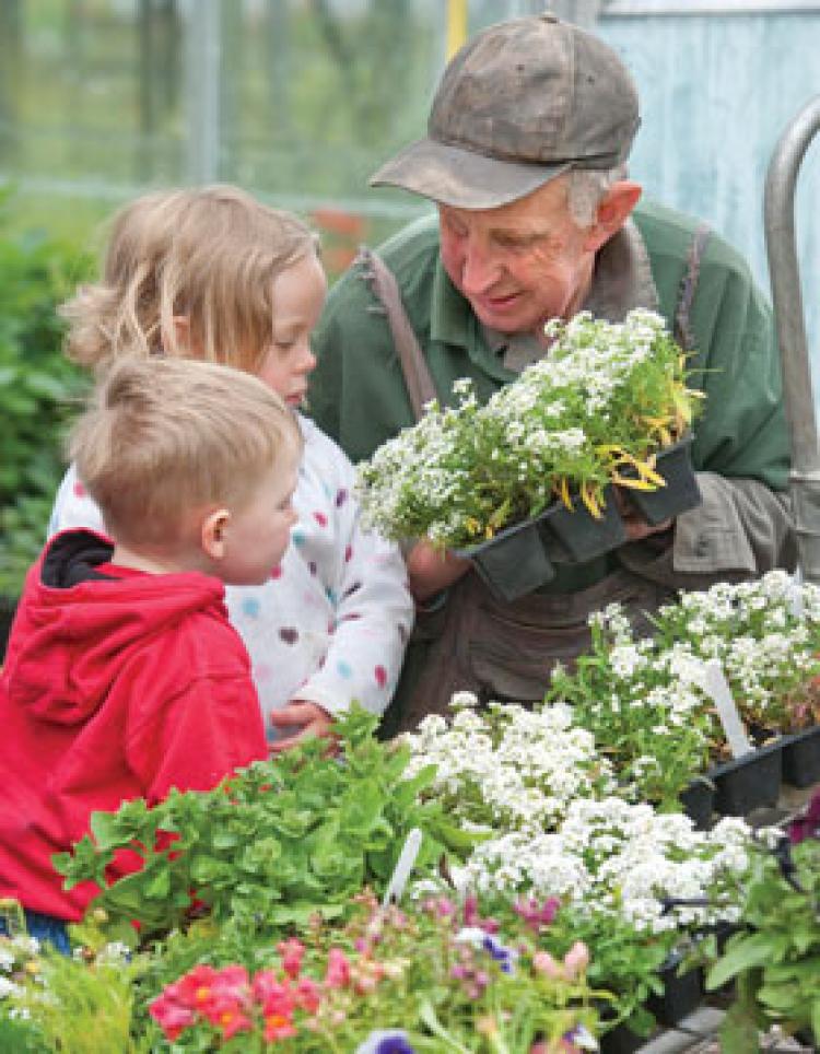 Gardener showing flowers to 2 children